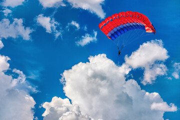 Paragliding parachuting sport in the blue cloudy sky.