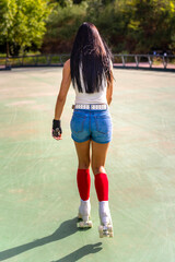 Rear photo of a middle aged skater woman roller skating in the park