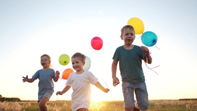 children run across the field. happy family kid dream concept. a group of children are run along road field with colorful balloons. guys run across field with large lifestyle colored balloons