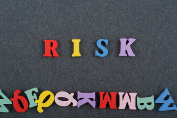 RISK word on black board background composed from colorful abc alphabet block wooden letters, copy space for ad text. Learning english concept.