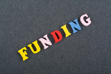 FUNDING word on black board background composed from colorful abc alphabet block wooden letters,...
