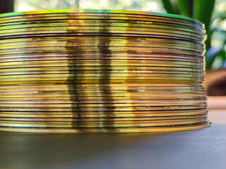 Close-up to interesting abstract patterns created by the rays of sunlight penetrating through a pile of CD arranged on the desk, Lodz, Poland.