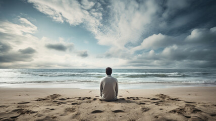 Fototapeta na wymiar Man sitting on a sand beach and looking to the sea. Peaceful place to relax and meditate. Calm weather.