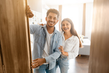 Indian couple smiling, standing by open door