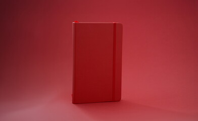 Red leather diary book on red background. Notebook with elastic band bookmark concept