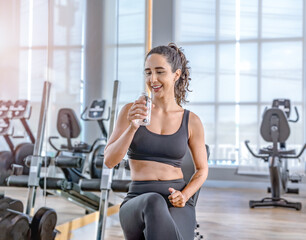 Fototapeta premium Exhausted woman in sportswear sitting at fitness training in .sporty athletic woman warm up training sitting near treadmill look aside in gym indoor Workout sport motivation