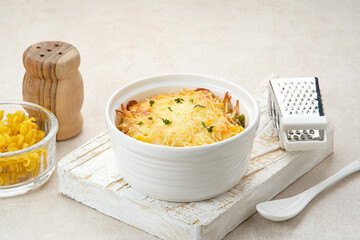 Baked macaroni and cheese on a white bowl with parmesan and herbs
