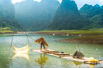 Fototapeta premium view of fishermen fishing on river in Thung mountain in Tra Linh, Cao Bang province, Vietnam with lake, cloudy, nature