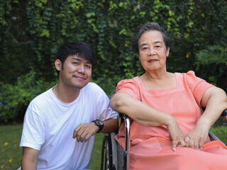 Obraz premium Asian senior woman sitting on wheelchair with her son in the garden.