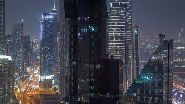 High-rise buildings on Sheikh Zayed Road in Dubai aerial night timelapse, UAE. Skyscrapers in international financial district and business bay from above. Houses and villas on a background