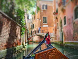 View from the front of the gondola to Venice canals, architecture and the bridge over the canal.