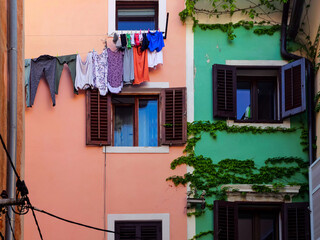 Fototapeta na wymiar A picturesque wall of a house in a European city, covered with ivy and with laundry drying on a line outside.
