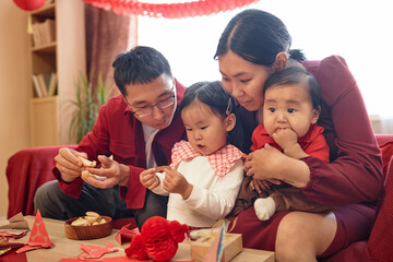 Portrait of happy Asian family with two children celebrating Chinese New Year together at home and...