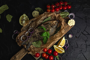 A top view of a dish of fried carp that is decorated with basil, cherry