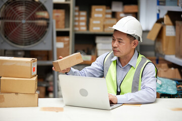 factory worker looking at cardboard box packaging in the warehouse storage