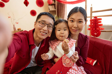 POV of happy Asian family wearing red on Chinese new year and taking selfie photo together at home...