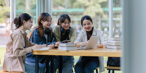 Group of young Asian college students sitting on a bench in a campus relaxation area, talking,...