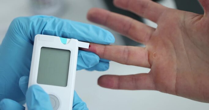 Doctor in rubber gloves measuring patient blood glucose using glucometer closeup 4k movie slow motion. Diagnosis and treatment of diabetes mellitus concept