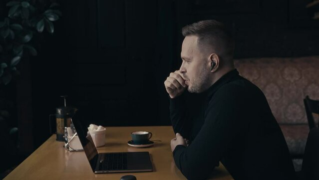 Portrait of an elegant man in a cafe with a laptop. A manager holds a video conference with colleagues or friends. Communication via video call.