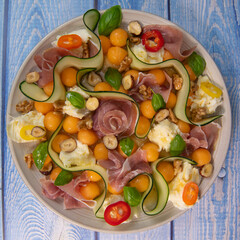 RECIPE FOR MELON, MOZARELLA, BASIL AND CURED HAM SALAD, CUCUMBER SLICE, ORANGE VINAIGRETTE. High quality photo