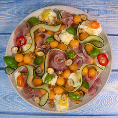 RECIPE FOR MELON, MOZARELLA, BASIL AND CURED HAM SALAD, CUCUMBER SLICE, ORANGE VINAIGRETTE. High quality photo
