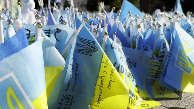 Many small flags of Ukraine with names of the dead war against russia. Memorial of the fallen soldiers, children, women in the center of Kyiv. Concept of tragedy and misfortune. Closeup