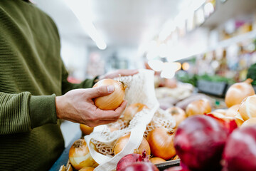 Close-up of man's hands picking onions in supermarket