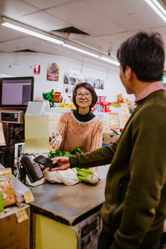 Man buying fresh produce from woman at supermarket counter