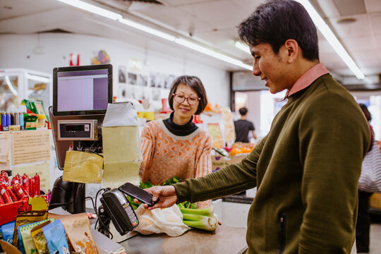 Man buying fresh produce from woman at supermarket counter