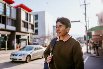 Smiling man with backpack on urban footpath