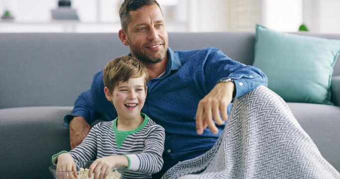 Family, popcorn and a father watching tv with his son on a sofa in the home living room together. Love, smile or happy with a man and boy child streaming a film, movie or video in an apartment