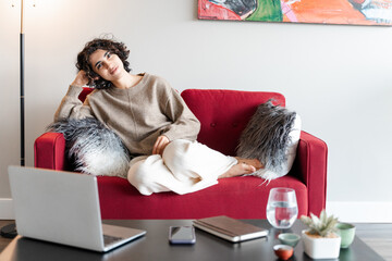 Serene lady looking at camera while relaxing on the sofa