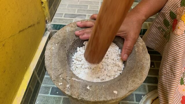 Pounding Umbi Gadung or Dioscorea hispida with mortar and pestle