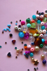 Various colorful beads on bright pink background. Top view.