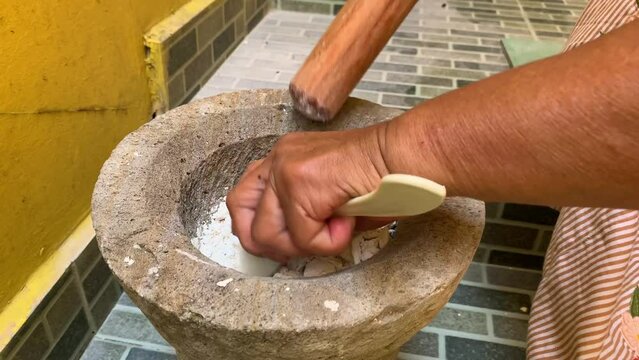 Pounding Umbi Gadung or Dioscorea hispida with mortar and pestle