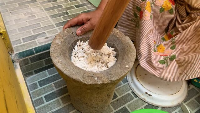 Pounding Umbi Gadung or Dioscorea hispida with mortar and pestle.