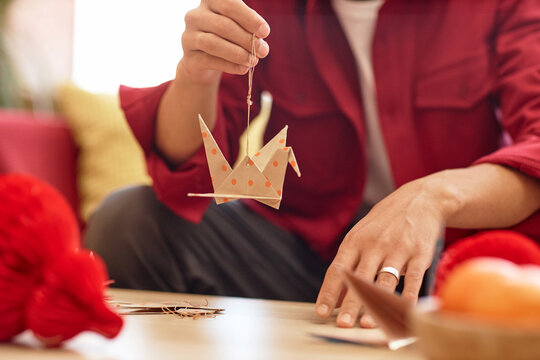 Closeup of unrecognizable Asian man holding paper crane as Chinese new year decoration, copy space