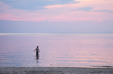 Fototapeta na wymiar boy in the sea at sunset walk