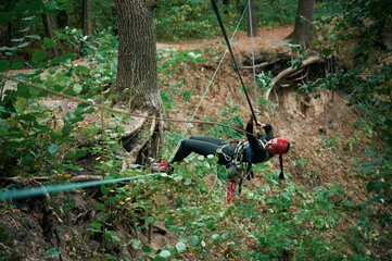 Climbing in the forest. Woman is in the forest using the safety equipment