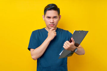 Serious professional young Asian male doctor or nurse wearing a blue uniform Hold patient diagnosis...