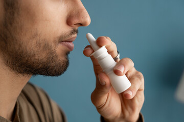Close-up of young arabic man spraying drops in nose