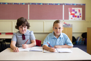 Two girl students writing in a primary school classroom