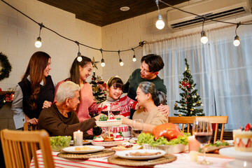 Happy and cheerful Asian family talking and smiling during Christmas dinner at home. Celebrate the holiday together Family reunions and reunions. Daughter is surrounded by warm family members.
