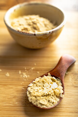 Close-up of a bowl and a wooden spoon with nutritional yeast, excellent vegan protein