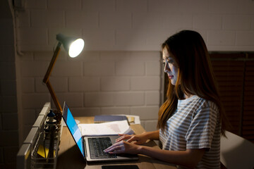 A woman is working late at night. - obrazy, fototapety, plakaty