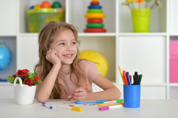 cute girl in the nursery draws at the table