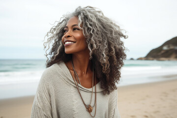 Ederly beautiful african aging mature woman with long gray hair enjoying walk along beach.