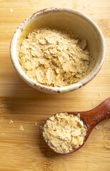 Close-up of a bowl and a wooden spoon with nutritional yeast, excellent vegan protein