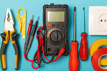 Electrician tools on background. Multimeter,construction tape,electrical tape, screwdrivers,pliers,an automatic insulation stripper, socket and LED lamp. Flatley. electrician concept.