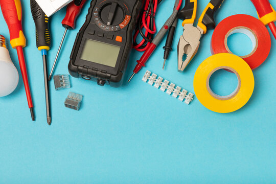 Electrician tools on background. Multimeter,construction tape,electrical tape, screwdrivers,pliers,an automatic insulation stripper, socket and LED lamp. Flatley. electrician concept.